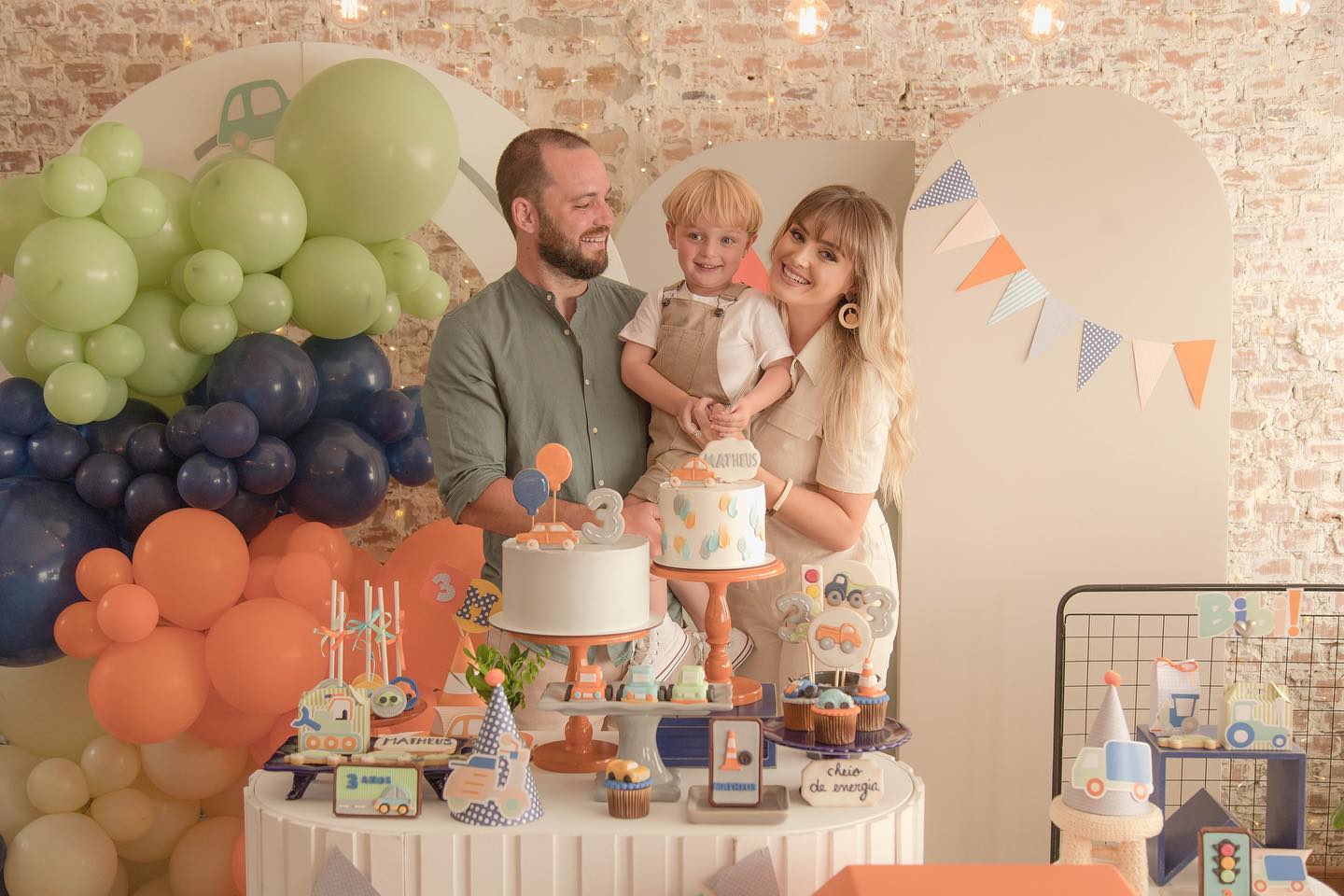 Pais com o filho na mesa do aniversário de três anos