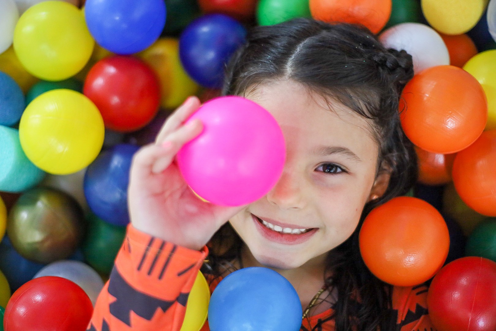 Menina brincando em uma piscina de bolinhas coloridas
