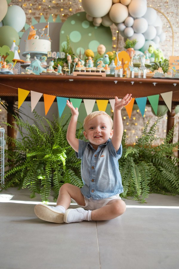 Criança sorrindo e levantando os braços em sua festa