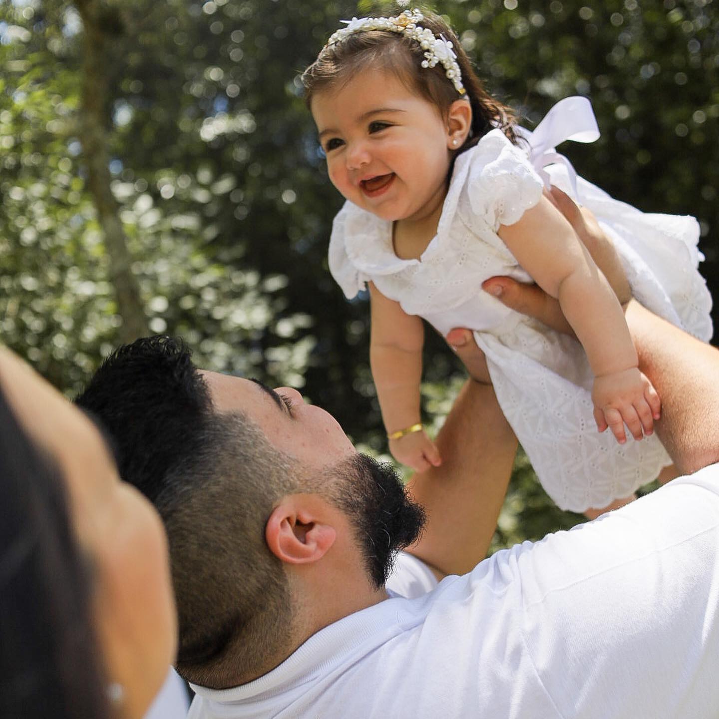 Pai levantando a filha sorridente ao ar livre