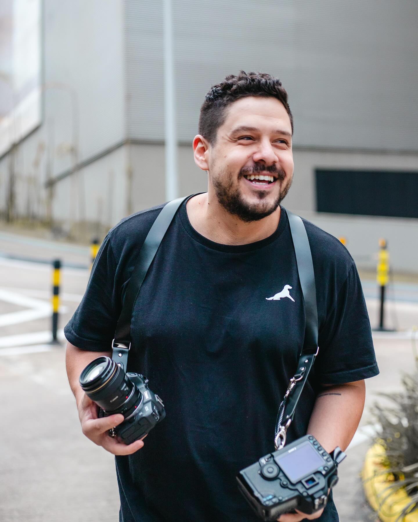 Renan Caumo sorrindo com suas câmeras fotográficas